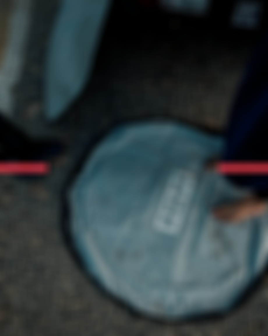 Barefoot person stands on a round, gray changing mat beside a car, with a car cover partially visible.