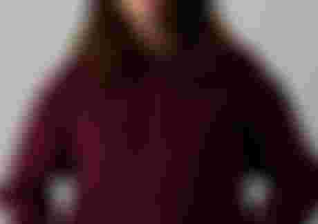 Woman wearing a dark red hoodie with ION logo and a light yellow fisherman beanie