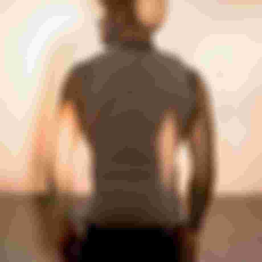 A person wearing a impact vest and helmet looks at a sunset on a beach. The image has a warm, dreamy double exposure effect.