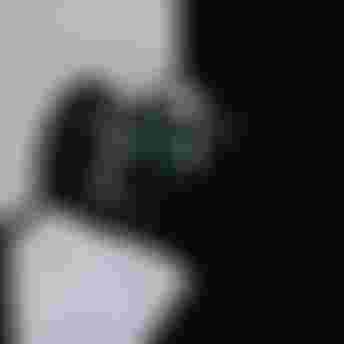 Black duffel bag with gray straps partially in shadow, resting on the ground near an open garage door, sunlight streaming in.