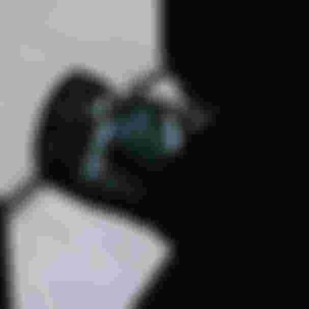 Black duffel bag with gray straps partially in shadow, resting on the ground near an open garage door, sunlight streaming in.