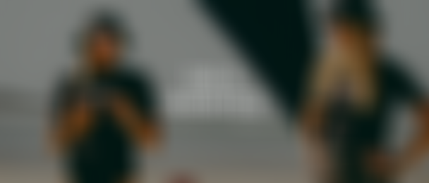 Two people wearing black bucket hats and shirts stand under a canopy at a beach, with the text "ION X SHEKITES" overlaid on the image.