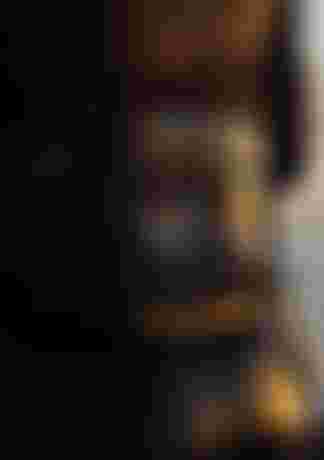 Close-up of a person wearing a wetsuit with a reflective waist belt, droplets on the surface, and wet hair in a sunset-lit scene.