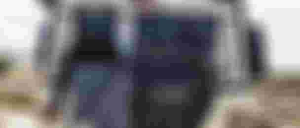 Rear view of an off-road vehicle with kite gear, including a harness, hat, and jacket, attached to the back. Desert landscape in the background.