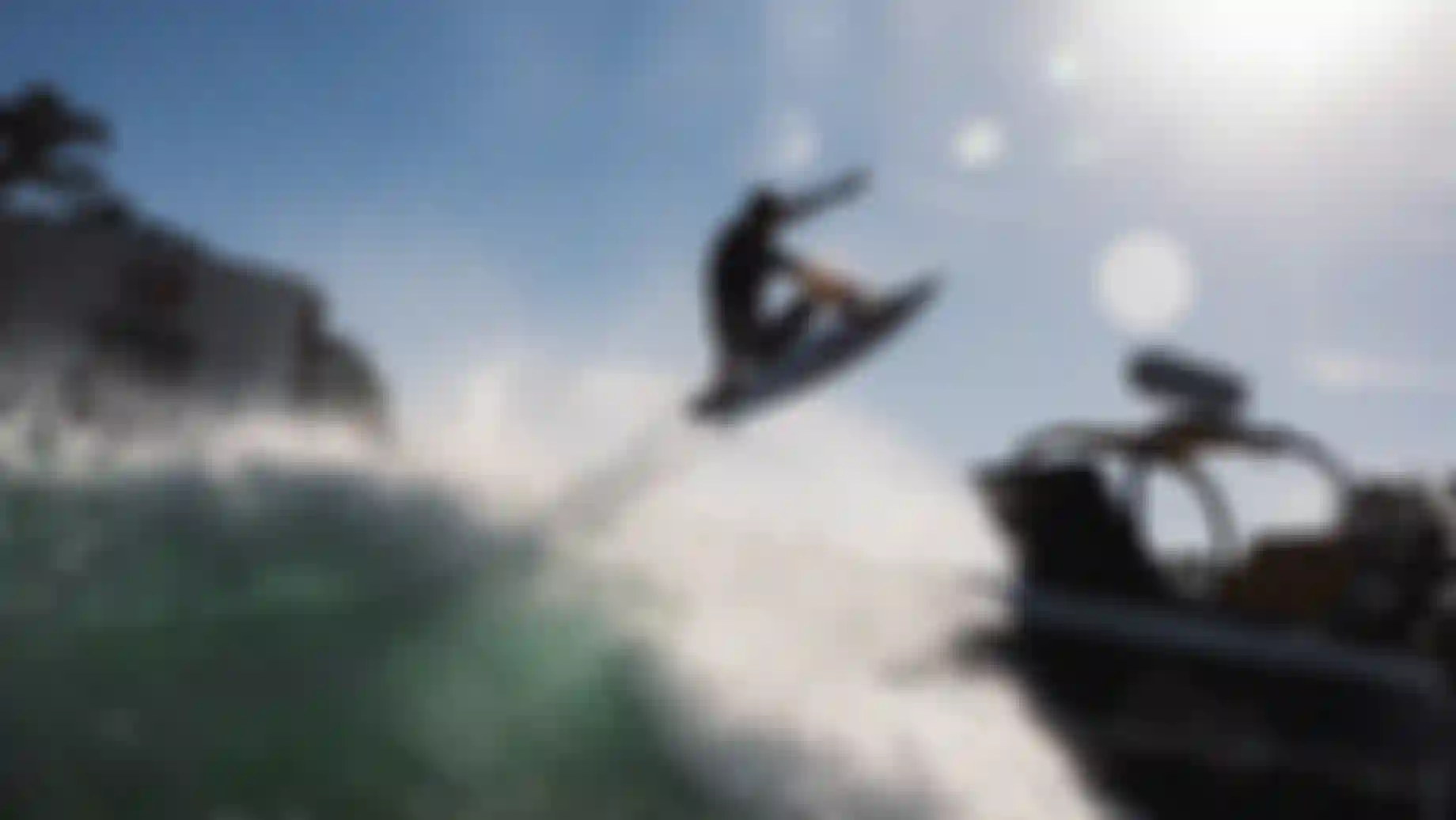 Surfer launching aerial maneuver off a breaking wave at the Waco surf park during a Swatch-sponsored competition event.