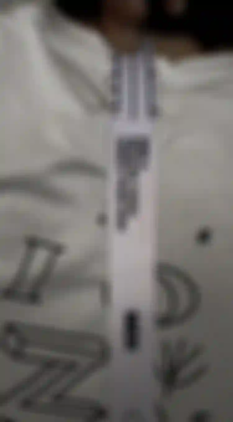 A person measuring the back of a white t-shirt with a measuring tape