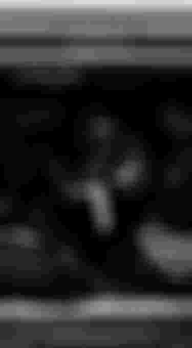 Black and white photo of a vehicle with its back doors open, showing bags and luggage packed tightly inside.