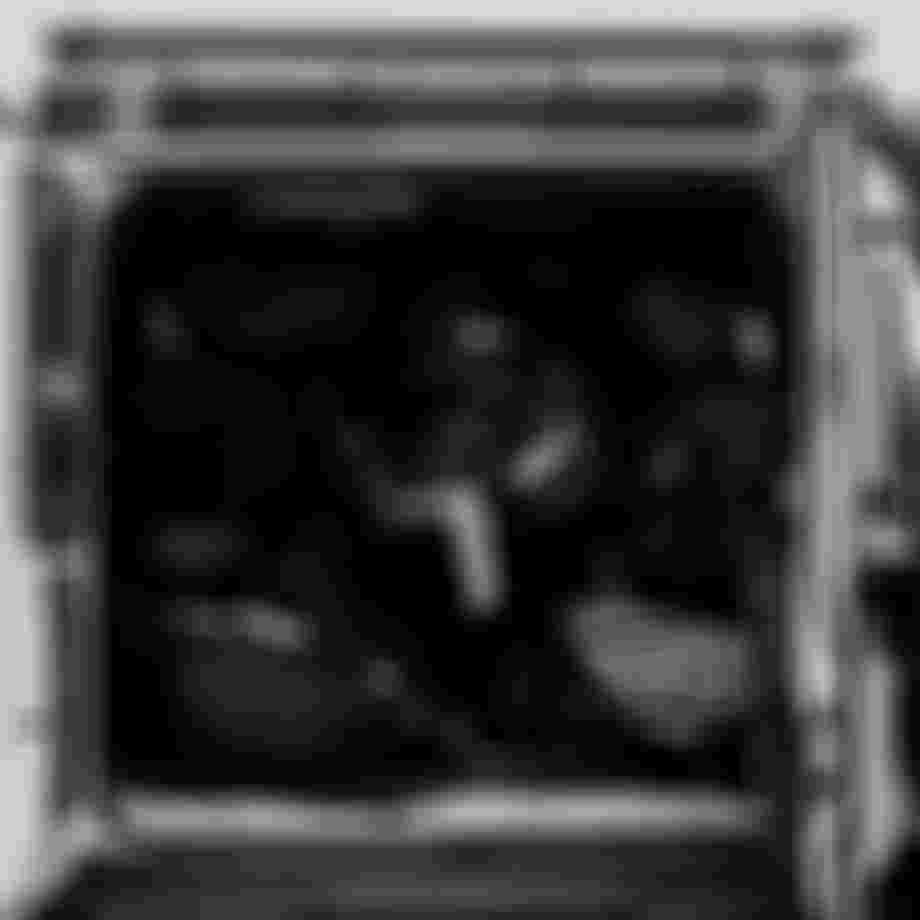 Black and white photo of a vehicle with its back doors open, showing bags and luggage packed tightly inside.