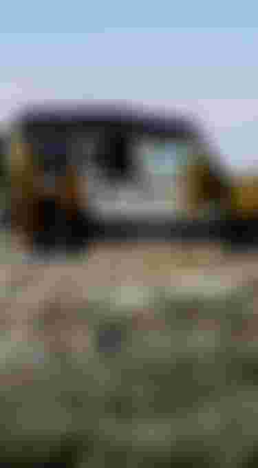 A rugged off-road vehicle with camping gear and clothes drying, parked on a rocky terrain under a cloudy sky.