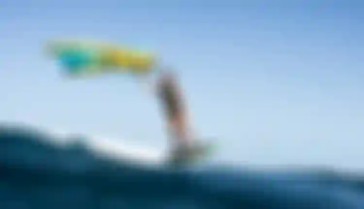 ION athlete Mo Chauvin winging over turquoise water in Guadeloupe, wearing an ION Amaze V-Back wetsuit.