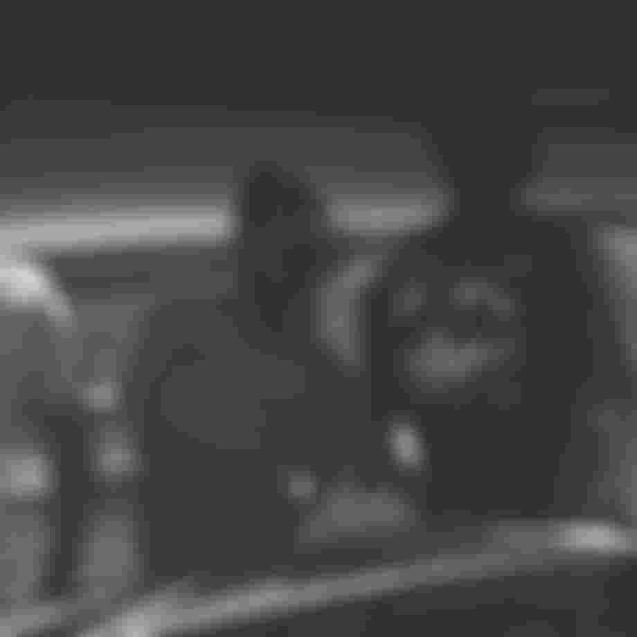 Three men leaning against a car photographed through the windshield