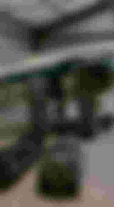 A small aircraft in a hangar with four large black duffel bags lined up on the floor in front of it.