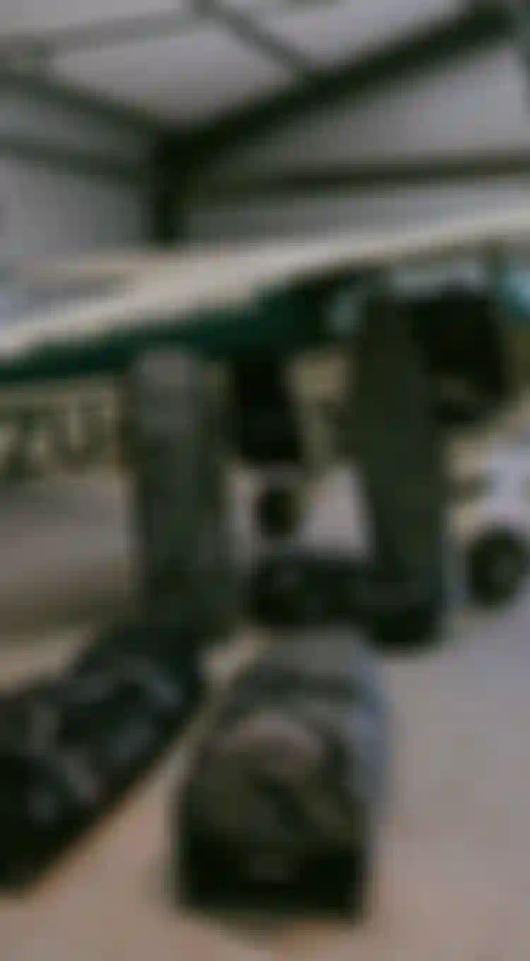 A small aircraft in a hangar with four large black duffel bags lined up on the floor in front of it.