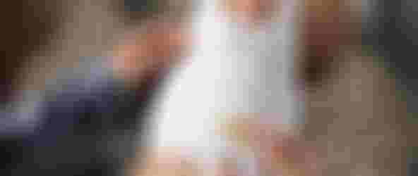 Person putting on a paper leg band with detailed instructions, seated on a gray carpet, wearing a blue shirt and white socks.