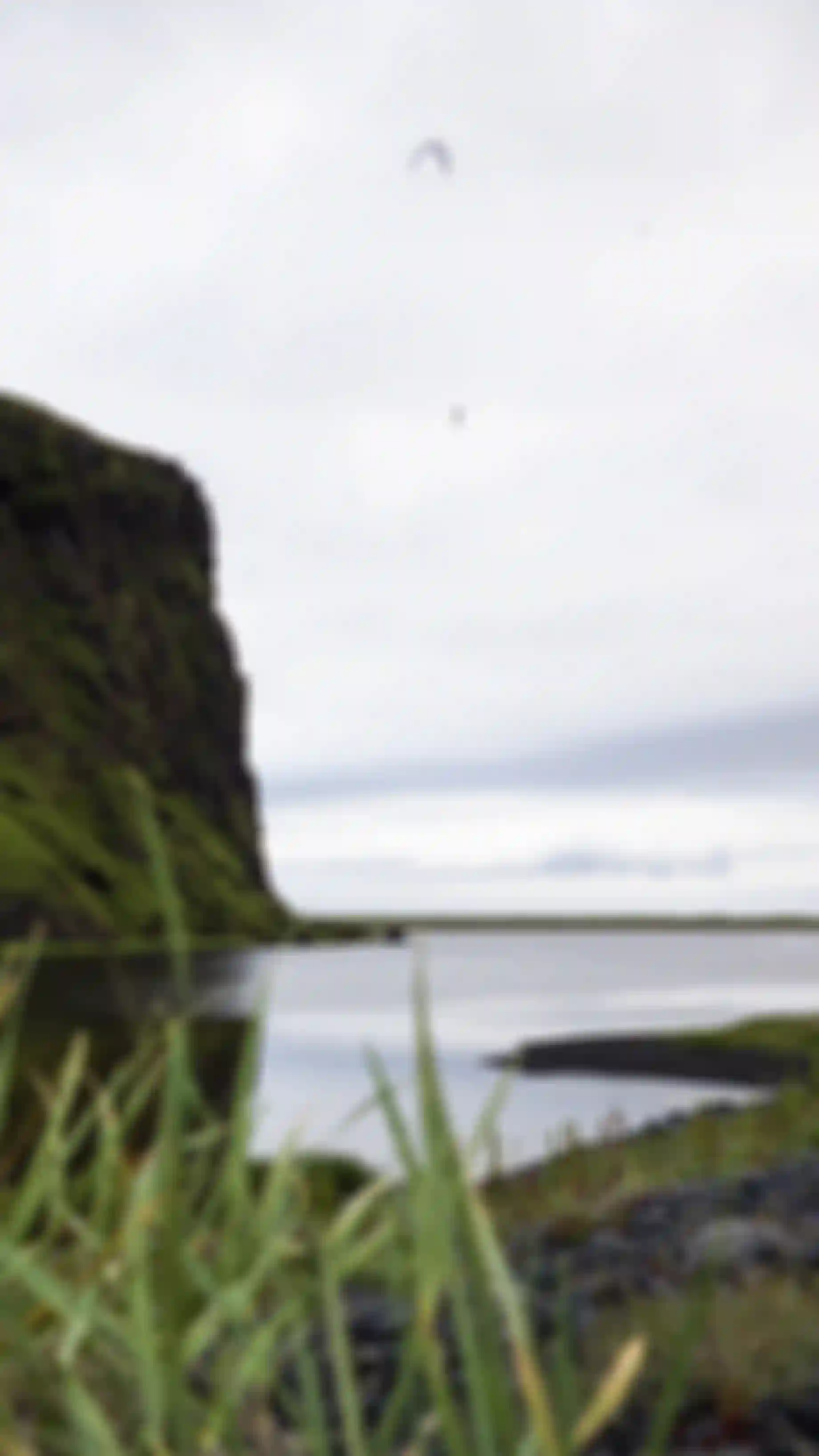 Kiterboarder hanging mid air next to a cliff