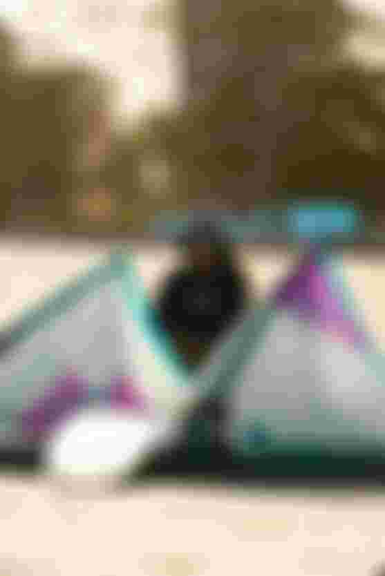 women kneeling on a beach with kite in front of her