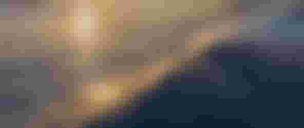 Surfer riding a wave at sunset with golden light reflecting on the water, creating a serene and dynamic coastal scene.