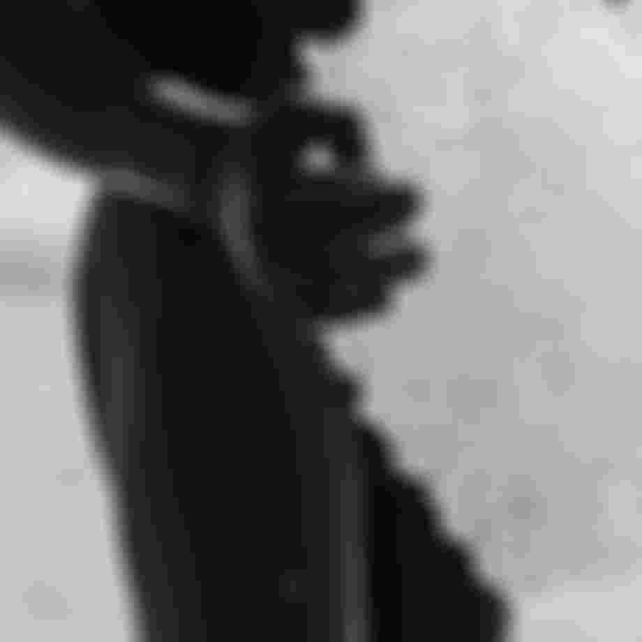 Close up image of a person wearing a black wetsuit and neoprene gloves carrying a block if ice in their hands