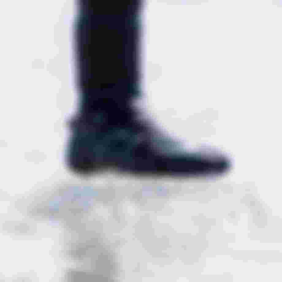 Close up of a worn neoprene boot standing on frozen water