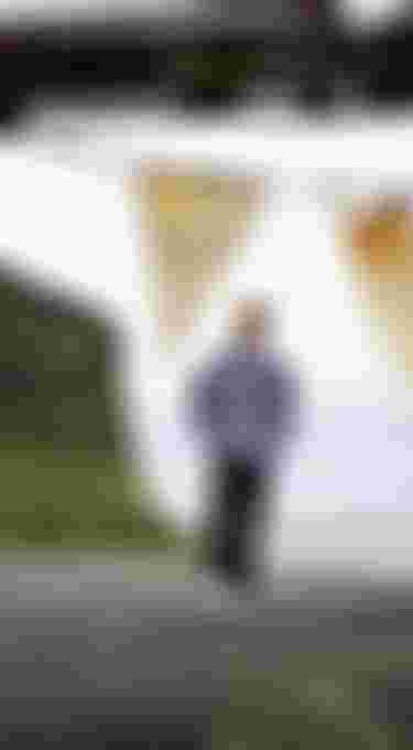 Man walking on a black beach with green hills in the background
