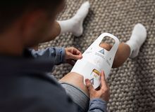 A person applying a white adhesive wrap to their knee while sitting on a carpet, wearing a blue shirt and white socks.
