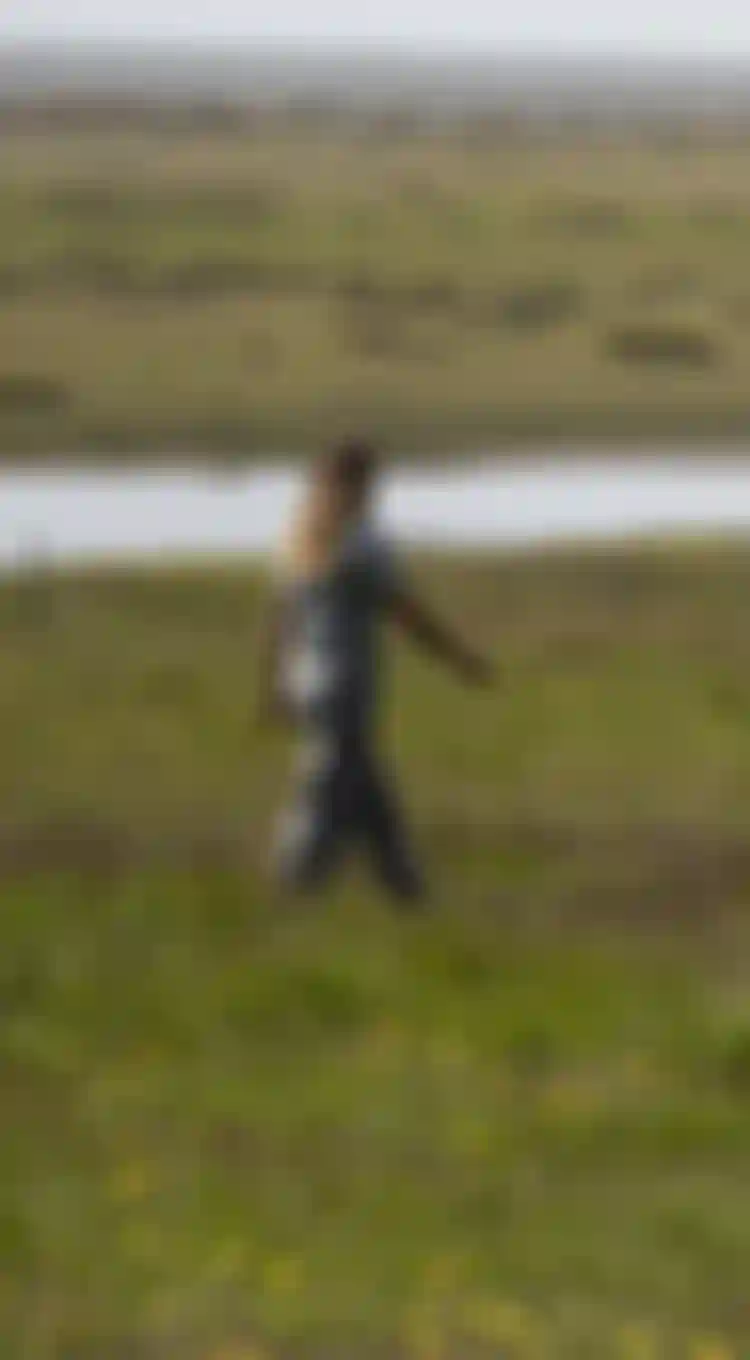 Woman walking on a grass field wearing a t-shirt