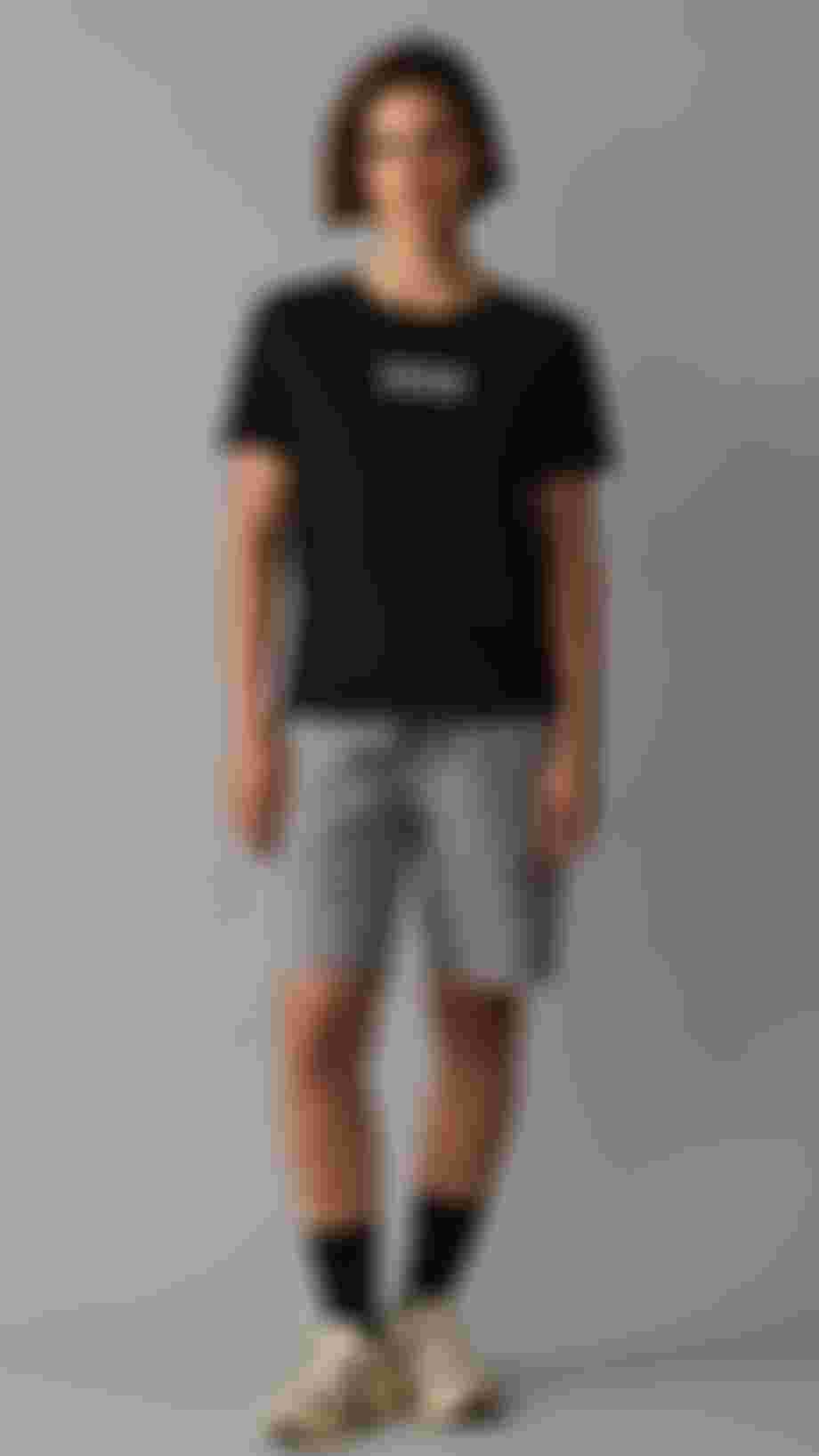 Woman with short brown hair standing in front of neutral grey background