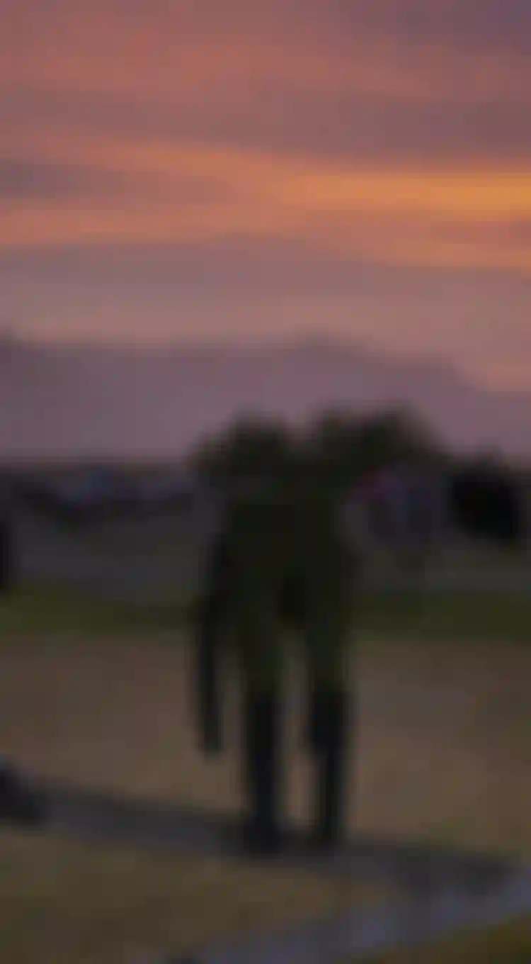 Sunset scenery in the background, wetsuits and kite harnesses hanging over a fence to dry