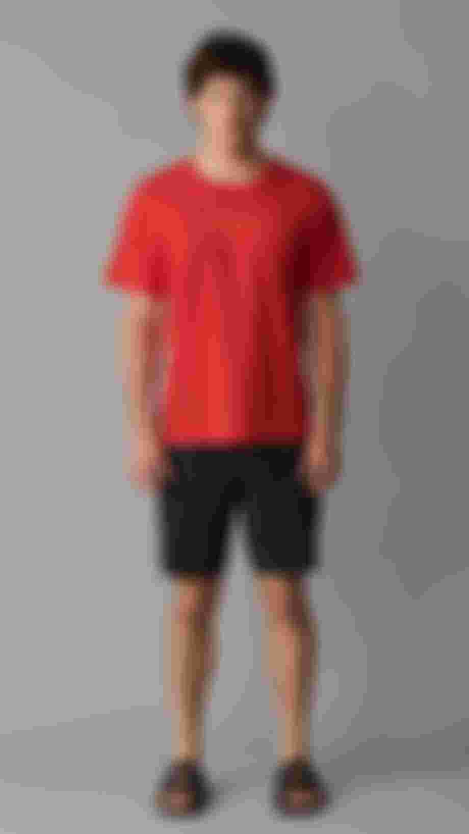 Man wearing a red tee standing in front of grey background