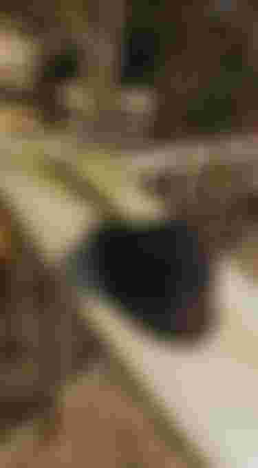 black bucket hat with white ION logo hanging on a fin of a surfboard which leans against a wall