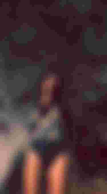 woman in a blue long sleeve swimsuit in front of trees with an analog grainy filter