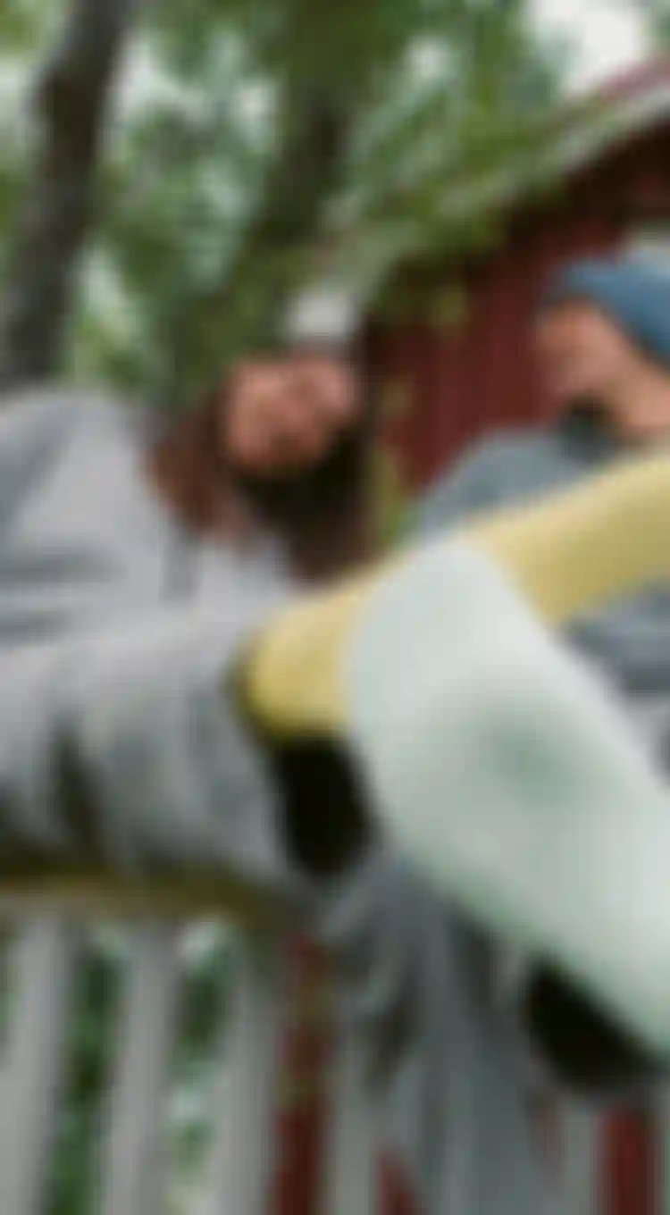 three people in socks laughing while sitting on a fence