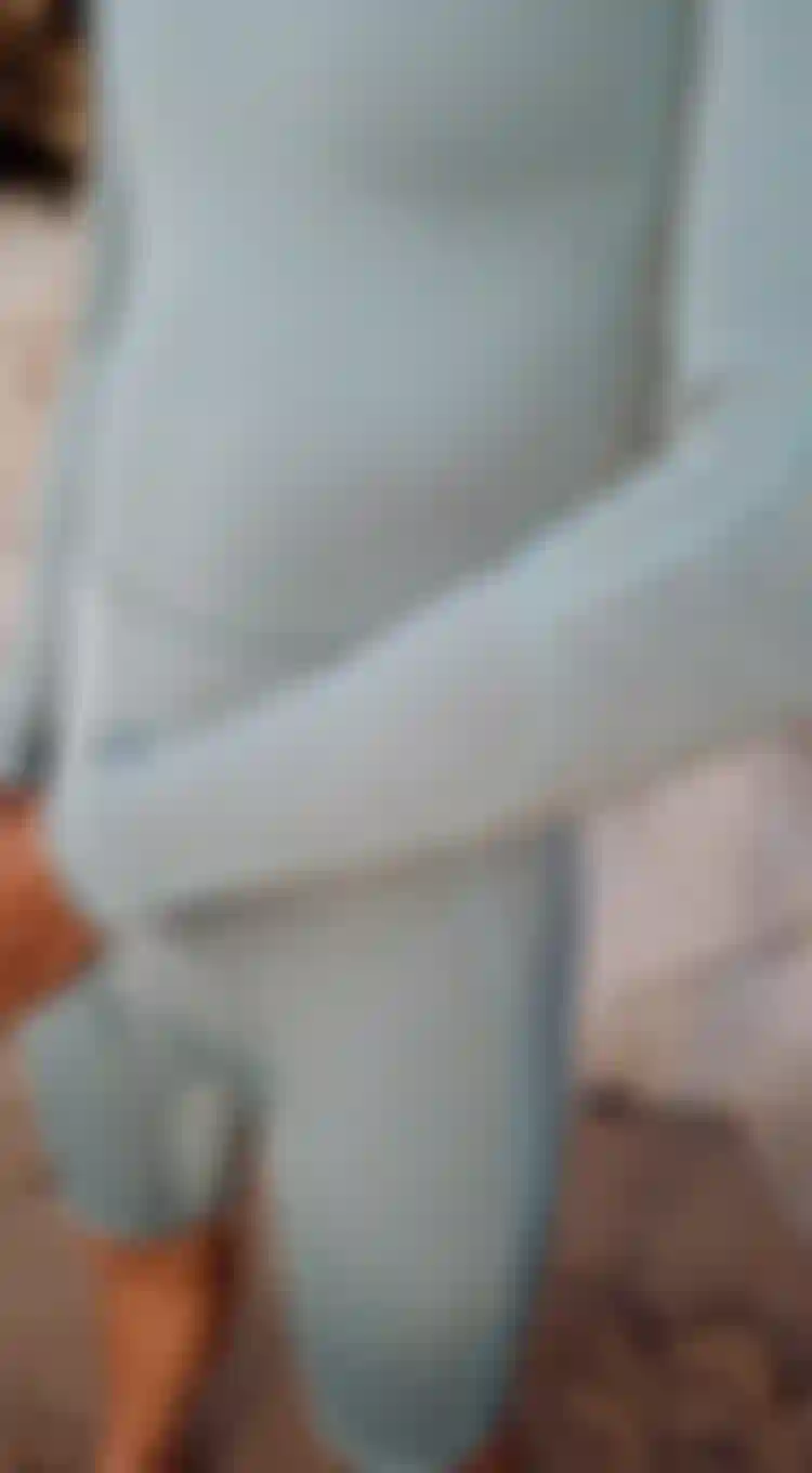 close up view of someone wearing a light green shorty wetsuit with long sleeves