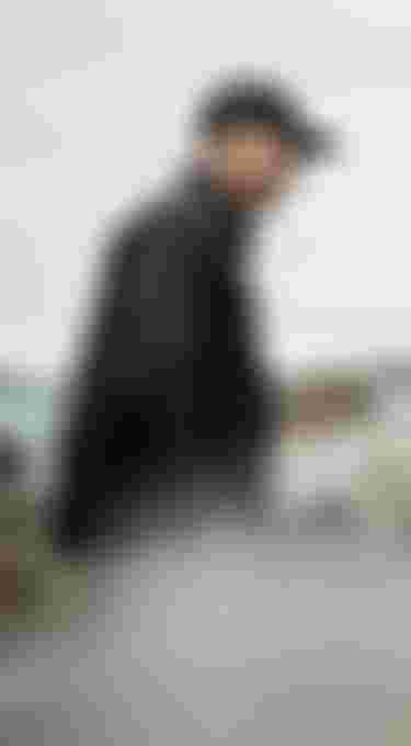 Two man in black jackets filming on the beach