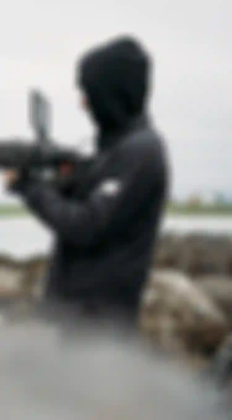 Two man in black jackets filming on the beach