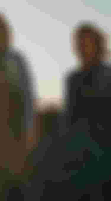 Two boys wearing blue wetsuits on a rocky beach