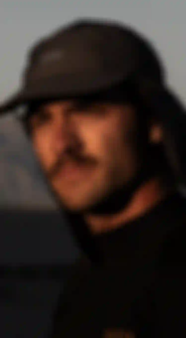 man with hat staring at the setting sun