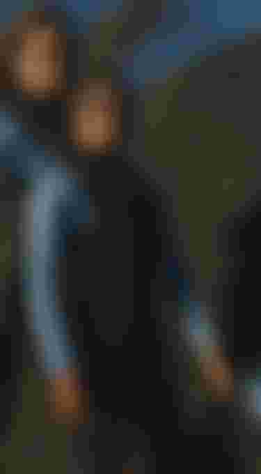 child wearing a blue wetsuit standing in front of rocks