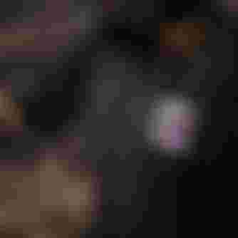 Person in a black shirt with a purple graphic, wearing a helmet, is focused on an activity outdoors.