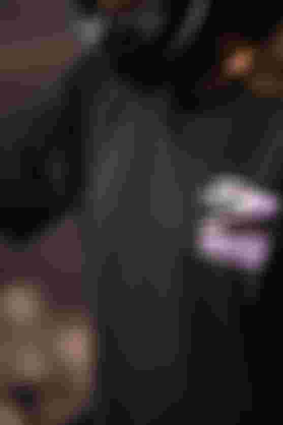 Person in a black shirt with a purple graphic, wearing a helmet, is focused on an activity outdoors.