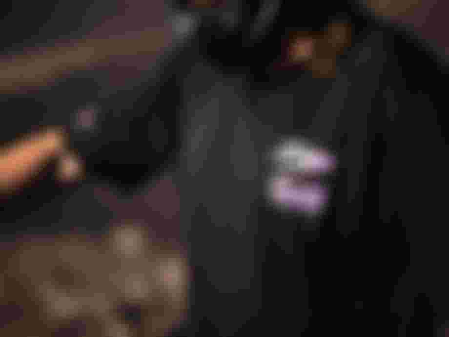 Person in a black shirt with a purple graphic, wearing a helmet, is focused on an activity outdoors.