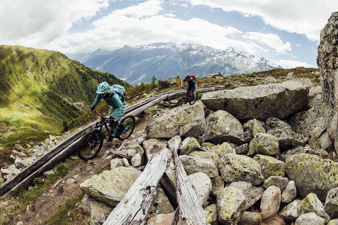 ION Bike Shelter windbreaker jacket in teal during mountain biking on an alpine trail