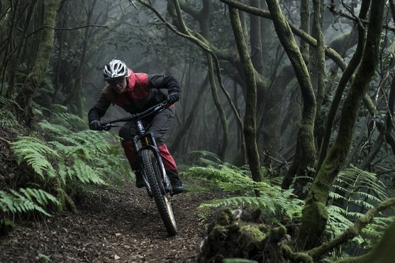 ION Shelter WMS softshell pants in dark charcoal during mountain biking in a misty forest