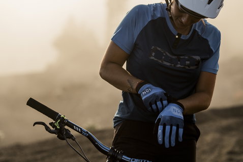 ION Scrub Fahrradhandschuhe in blau beim Mountainbiken auf einem staubigen Trail