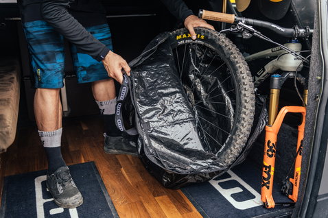 Sac roue ION Universal Wheel Bag en noir lors du chargement d'une roue VTT dans un van