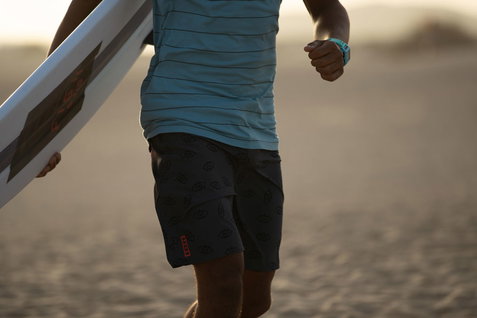 ION Slade boardshorts in dark charcoal during kitesurfing on a sandy beach at golden hour