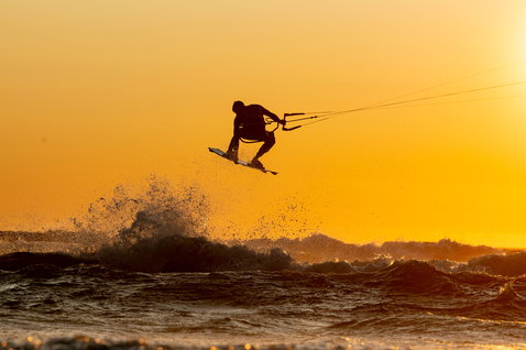 ION Element 2/2mm Backzip Shorty LS Neoprenanzug beim Kitesurfen im goldenen Abendlicht