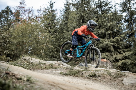 Genouillères ION K-Pact junior lors d'une descente en VTT sur sentier forestier rocheux
