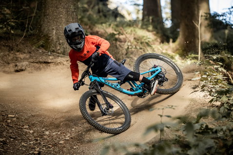 Genouillères ION K-Pact youth en vélo de montagne sur sentier forestier en noir