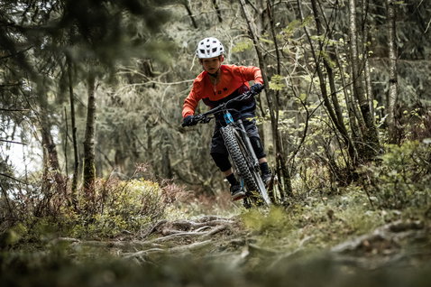 ION Scrub youth bike gloves in black during mountain biking on a forest trail